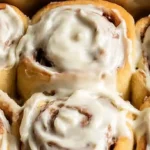 Freshly baked gluten-free cinnamon rolls in a baking dish with cream cheese frosting