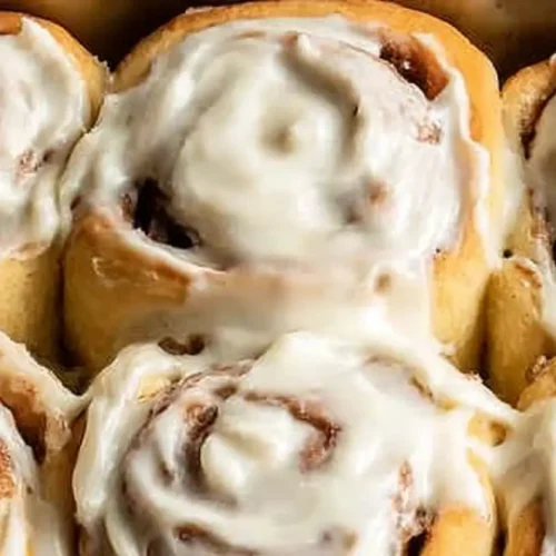 Freshly baked gluten-free cinnamon rolls in a baking dish with cream cheese frosting