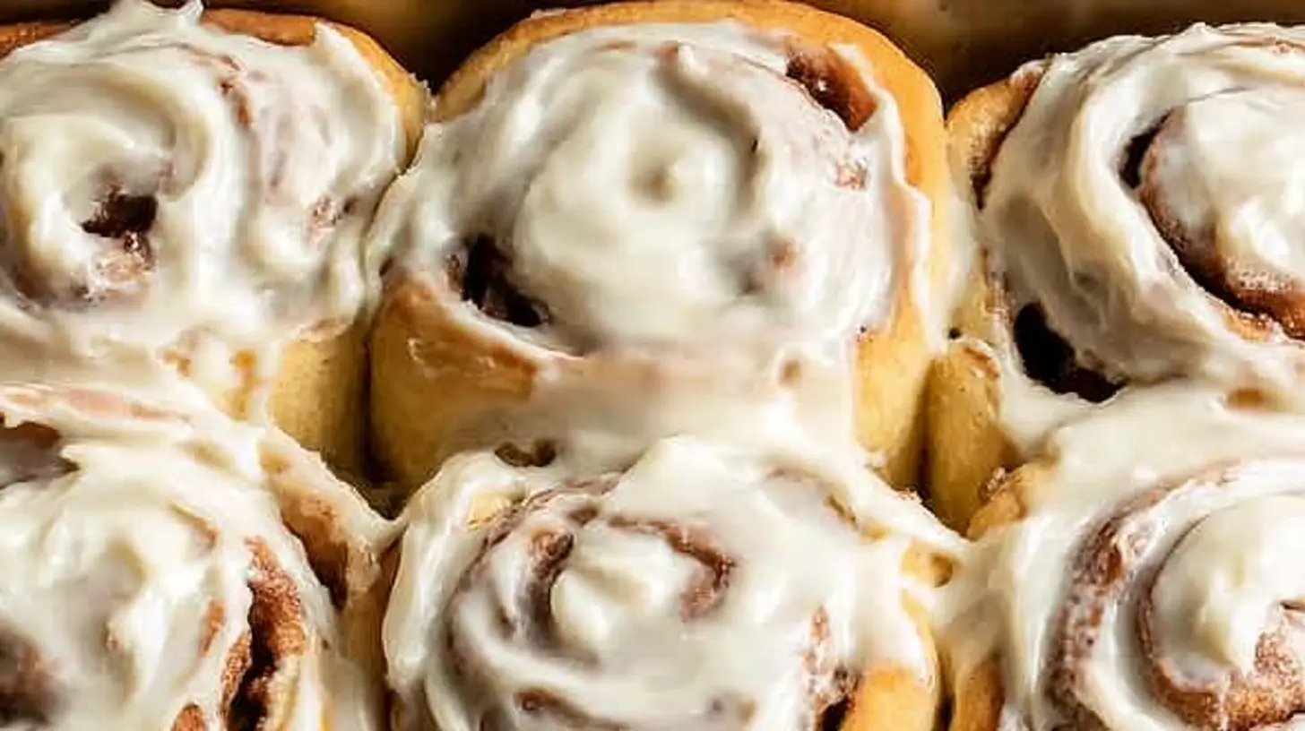 Freshly baked gluten-free cinnamon rolls in a baking dish with cream cheese frosting