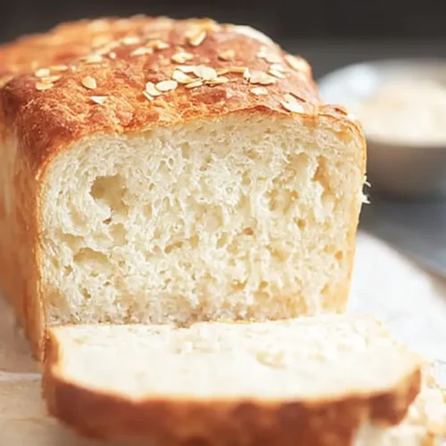 Freshly baked gluten-free dairy-free bread RECIPES loaf sliced on a wooden board, showcasing a soft, airy crumb and golden crust.