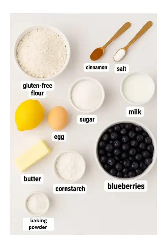Flat lay of gluten free baking ingredients including flour, butter, sugar, and spices on a white background