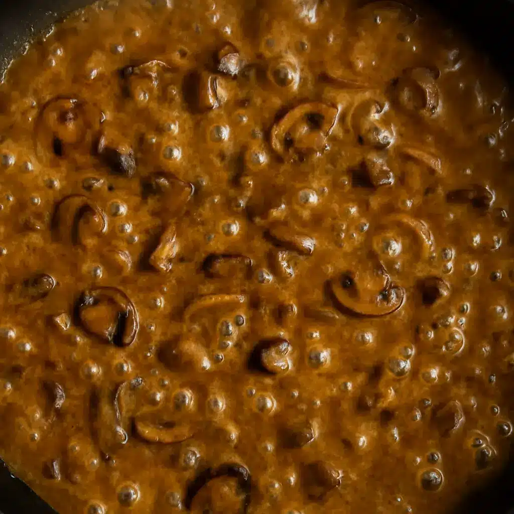 Sauce onctueuse en train de mijoter dans une poêle, formant de petites bulles à la surface.