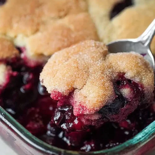 Close-up of a freshly baked gluten free blueberry cobbler with golden topping and juicy berries in a white baking dish