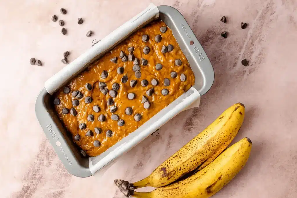 Gluten free pumpkin banana bread batter topped with chocolate chips in a loaf pan
